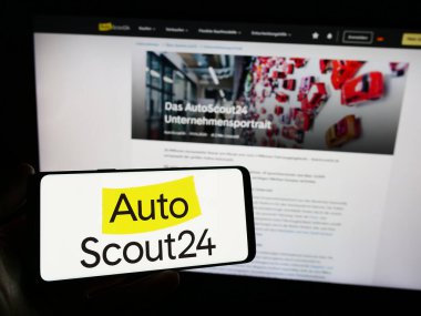 Stuttgart, Almanya - 11-14-2023: İnternet sitesi önünde üzerinde Alman otomobil çevrimiçi pazar şirketi AutoScout24 GmbH logosu bulunan kişi. Telefon ekranına odaklan.