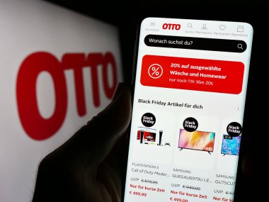 Stuttgart, Almanya - 11-14-2023: Alman posta sipariş şirketi Otto GmbH Co KG 'nin internet sayfası ile cep telefonu tutan kişi iş logosu önünde. Telefon ekranının merkezine odaklan.