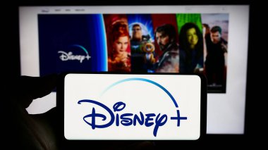 Stuttgart, Almanya - 11-14-2023: İş sayfasının önünde ABD 'li videolu yayın servisi Disney Plus' ın logosuyla cep telefonu tutan kişi. Telefon ekranına odaklan.