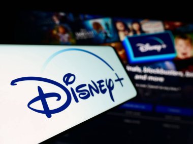 Stuttgart, Almanya - 11-14-2023: İş sitesinin önünde üzerinde Amerikan video-talep yayın servisi Disney Plus logosu bulunan cep telefonu. Telefon ekranının soluna odaklan.