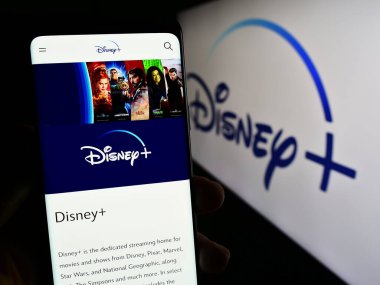 Stuttgart, Almanya - 11-14-2023: Cep telefonunda ABD 'nin talep üzerine video yayınlama servisi Disney Plus' ın logo önündeki web sayfası bulunan kişi. Telefon ekranının merkezine odaklan.