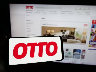Stuttgart, Almanya - 11-14-2023: Alman posta sipariş şirketi Otto GmbH Co KG 'nin logosuna sahip akıllı telefon sahibi kişi web sitesi önünde. Telefon ekranına odaklan.