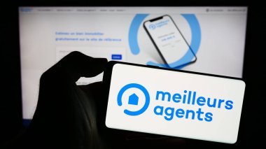Stuttgart, Almanya - 11-15-2023: Fransız emlak platformu şirketi MeilleursAgents 'in logosunun bulunduğu cep telefonu sahibi kişi iş sayfası önünde. Telefon ekranına odaklan.