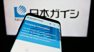 Stuttgart, Almanya - 11-15-2023: Japon seramik şirketi NGK Insulators Ltd. 'nin web sitesi ile ticaret logosu önünde akıllı telefon. Telefon ekranının sol üst kısmına odaklan.