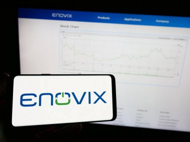 Stuttgart, Almanya - 09-25-2023: Amerikan batarya şirketi Enovix Corporation 'ın logosuna sahip cep telefonu sahibi kişi iş sayfasının önünde. Telefon ekranına odaklan.