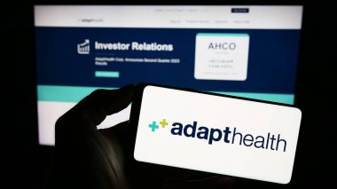 Stuttgart, Almanya - 09-25-2023: ABD 'li sağlık şirketi AdaptHealth LLC' nin logosuna sahip akıllı telefon sahibi kişi web sitesi önünde. Telefon ekranına odaklan.
