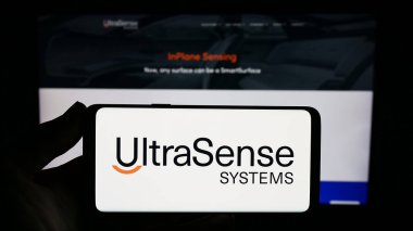 Stuttgart, Almanya - 09-28-2023: İnternet sitesi önünde üzerinde ABD sensör teknolojisi şirketi UltraSense Systems Inc. 'in logosu bulunan akıllı telefon sahibi kişi. Telefon ekranına odaklan.