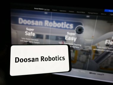 Stuttgart, Almanya - 09-28-2023: Koreli robot şirketi Doosan Robotics Inc. 'in logosunun bulunduğu cep telefonu sahibi kişi iş sayfasının önünde. Telefon ekranına odaklan.