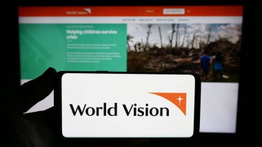 Stuttgart, Almanya - 10-06-2023: İnternet sitesi önünde World Vision International adlı yardım kuruluşunun logosunu taşıyan kişi. Telefon ekranına odaklan.