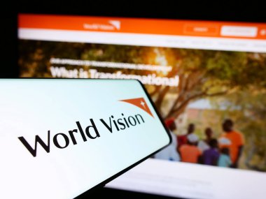 Stuttgart, Almanya - 10-06-2023: İnternet sitesi önünde World Vision International 'ın logosu olan cep telefonu. Telefon ekranının merkez soluna odaklan.