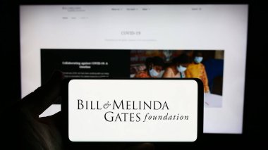 Stuttgart, Almanya - 10-06-2023: İnternet sitesinin önünde üzerinde American Bill ve Melinda Gates Foundation (BMGF) logosu bulunan kişi. Telefon ekranına odaklan.