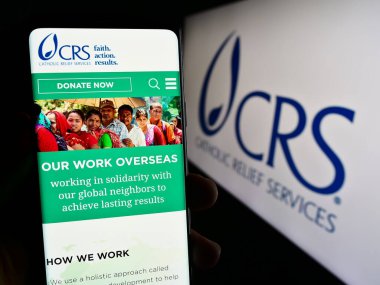 Stuttgart, Almanya - 10-06-2023: Logo önünde yardım derneği (CRS) web sitesi ile cep telefonu tutan kişi. Telefon ekranının merkezine odaklan.