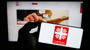 Stuttgart, Almanya - 10-08-2023: Alman örgütü Deutscher Caritasverband E.V. logosuyla cep telefonu tutan kişi Web sayfasının önünde. Telefon ekranına odaklan.