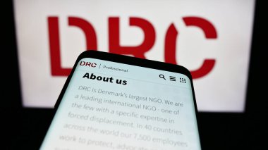 Stuttgart, Almanya - 10-08-2023: İnsani yardım örgütü Danimarka Mülteci Konseyi (DRC) web sitesi logosu önünde cep telefonu. Telefon ekranının sol üst kısmına odaklan.