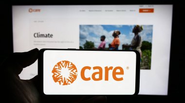 Stuttgart, Almanya - 10-08-2023: İnternet sayfasının önünde CARE International adlı insani yardım kuruluşunun logosuna sahip kişi. Telefon ekranına odaklan.