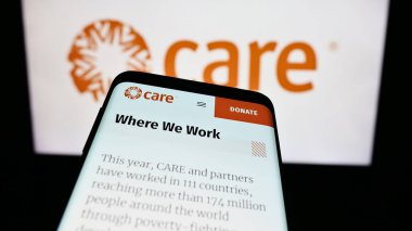 Stuttgart, Almanya - 10-08-2023: İnsani yardım kuruluşu CARE International 'ın web sitesiyle birlikte logo önünde cep telefonu. Telefon ekranının sol üst kısmına odaklan.