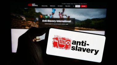 Stuttgart, Almanya - 10-09-2023: İnternet sayfası önünde İngiliz Kölelik Karşıtı Uluslararası Örgüt logosu olan kişi. Telefon ekranına odaklan.