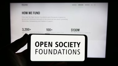 Stuttgart, Germany - 10-09-2023: Person holding smartphone with logo of organization Open Society Foundations (OSF) in front of website. Focus on phone display. clipart