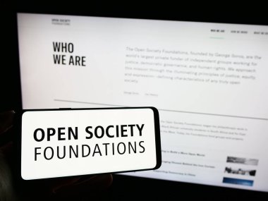 Stuttgart, Germany - 10-09-2023: Person holding mobile phone with logo of organization Open Society Foundations (OSF) in front of web page. Focus on phone display. clipart