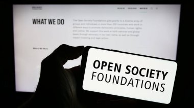 Stuttgart, Almanya - 10-09-2023: İnternet sayfası önünde üzerinde Açık Toplum Vakfı (OSF) logosu bulunan kişi. Telefon ekranına odaklan.