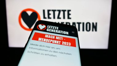 Stuttgart, Germany - 10-10-2023: Smartphone with webpage of climate change activist group Letzte Generation (LG) in front of logo. Focus on top-left of phone display. clipart