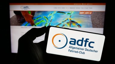 Stuttgart, Almanya - 10-10-2023: Allgemeiner Deutscher Fahrrad-Club E.V. logosuna sahip akıllı telefon sahibi kişi Web sitesinin önünde (ADFC). Telefon ekranına odaklan.