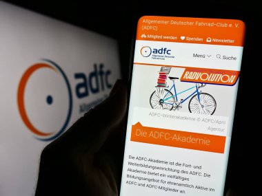 Stuttgart, Almanya - 10-10-2023: Allgemeiner Deutscher Fahrrad-Club E.V. web sayfası ile cep telefonu tutan kişi (ADFC) Logonun önünde. Telefon ekranının merkezine odaklan.