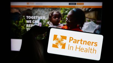 Stuttgart, Almanya - 10-10-2023: İnternet sayfası önünde ABD 'li Partners in Health (PIH) örgütünün logosu olan cep telefonu sahibi. Telefon ekranına odaklan.
