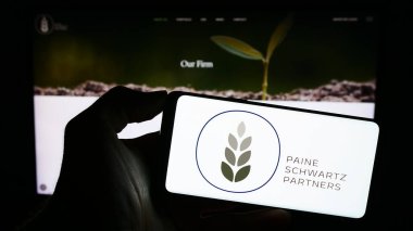Stuttgart, Almanya - 10-11-2023: Amerikan yatırım şirketi Paine Schwartz Partners LLC 'nin logosunun bulunduğu cep telefonu sahibi kişi web sayfasının önünde. Telefon ekranına odaklan.