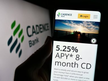 Stuttgart, Germany - 10-11-2023: Person holding cellphone with webpage of US financial services company Cadence Bank in front of logo. Focus on center of phone display. clipart