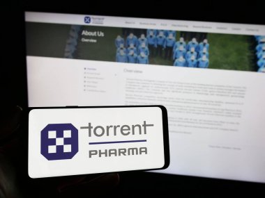 Stuttgart, Almanya - 10-11-2023: Hint şirketi Torrent Pharmaceuticals Limited 'in logosuna sahip akıllı telefon sahibi kişi web sitesinin önünde. Telefon ekranına odaklan.