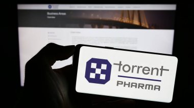 Stuttgart, Almanya - 10-11-2023: Hint firması Torrent Pharmaceuticals Limited 'in logosunun bulunduğu cep telefonu sahibi kişi iş sayfasının önünde. Telefon ekranına odaklan.
