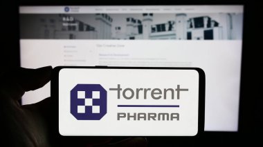 Stuttgart, Almanya - 10-11-2023: Hintli firma Torrent Pharmaceuticals Limited 'in logosuyla cep telefonu tutan kişi iş sayfasının önünde. Telefon ekranına odaklan.