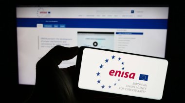 Stuttgart, Almanya - 10-16-2023: İnternet sayfası önünde Avrupa Birliği Siber Güvenlik Ajansı (ENISA) logosu bulunan kişi. Telefon ekranına odaklan.
