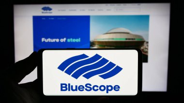 Stuttgart, Almanya - 10-16-2023: Avustralyalı şirket BlueScope Steel Limited 'in logosuna sahip akıllı telefon sahibi kişi web sitesinin önünde. Telefon ekranına odaklan.