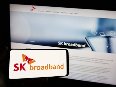 Stuttgart, Almanya - 10-16-2023: Koreli telekomünikasyon şirketi SK Broadband Inc. 'in logosunu elinde tutan kişi. Telefon ekranına odaklan.