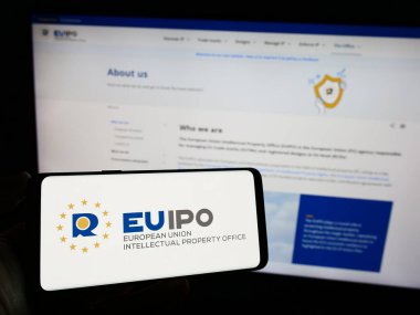 Stuttgart, Almanya - 10-17-2023: İnternet sayfası önünde Avrupa Birliği Fikir Eserleri Ofisi (EUIPO) logosu bulunan cep telefonu sahibi kişi. Telefon ekranına odaklan.
