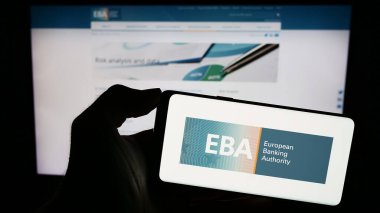 Stuttgart, Almanya - 10-20-2023: İnternet sayfası önünde AB kurumunun Avrupa Bankacılık Dairesi (EBA) logosuna sahip cep telefonu sahibi kişi. Telefon ekranına odaklan.