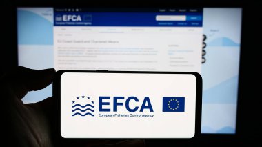 Stuttgart, Almanya - 10-20-2023: İnternet sayfası önünde AB kurumu Avrupa Balıkçılık Kontrol Dairesi 'nin (EFCA) logosuyla cep telefonu tutan kişi. Telefon ekranına odaklan.