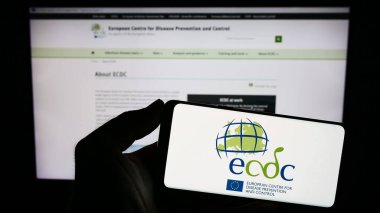 Stuttgart, Almanya - 10-25-2023: İnternet sitesi önünde Avrupa Hastalık Önleme ve Kontrol Merkezi (ECDC) logosu bulunan kişi. Telefon ekranına odaklan.