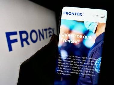 Stuttgart, Almanya - 10-25-2023: Logo önünde Avrupa Sınır ve Sahil Güvenlik Ajansı (Frontex) web sayfası bulunan akıllı telefon sahibi kişi. Telefon ekranının merkezine odaklan.