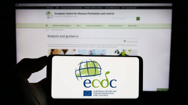Stuttgart, Almanya - 10-25-2023: İnternet sayfası önünde Avrupa Hastalık Önleme ve Kontrol Merkezi (ECDC) logosu bulunan cep telefonu sahibi kişi. Telefon ekranına odaklan.
