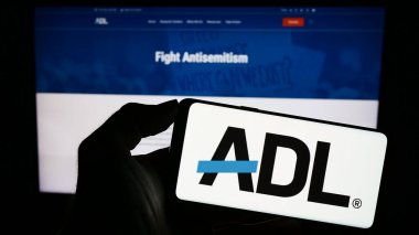 Stuttgart, Germany - 10-27-2023: Person holding mobile phone with logo of civil rights organisation Anti-Defamation League (ADL) in front of web page. Focus on phone display. clipart