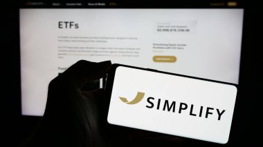 Stuttgart, Almanya - 10-28-2023: ABD 'li yatırım şirketi Basitleştirin Varlık Yönetimi A.Ş.' nin logosuyla cep telefonu sahibi kişi iş sayfasının önünde. Telefon ekranına odaklan.