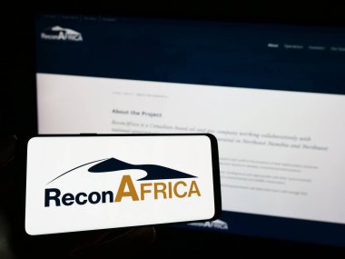 Stuttgart, Almanya - 10-28-2023: Reconnaissance Energy Africa Ltd. (Keşif Afrika) adlı şirketin logosuna sahip cep telefonu sahibi kişi web sayfasının önünde. Telefon ekranına odaklan.