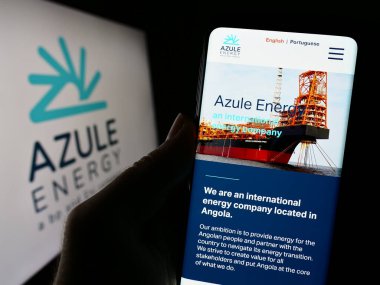 Stuttgart, Almanya - 10-28-2023: Angolan petrol şirketi Azule Energy 'nin web sayfası ile iş logosu önünde cep telefonu tutan kişi. Telefon ekranının merkezine odaklan.