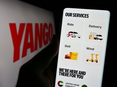 Stuttgart, Almanya - 10-28-2023: İş logosu önünde Yango firmasının web sitesi ile akıllı telefon tutan kişi. Telefon ekranının merkezine odaklan.