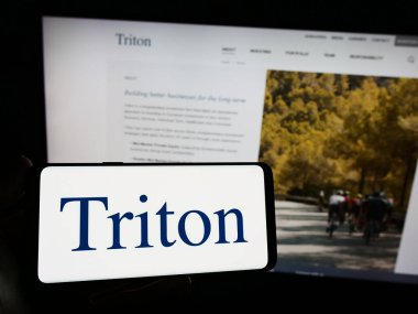 Stuttgart, Almanya - 10-28-2023: Web sitesi önünde yatırım şirketi Triton Partners 'ın logosuna sahip kişi. Telefon ekranına odaklan.