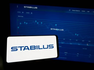 Stuttgart, Almanya - 10-29-2023: Alman hareket kontrol şirketi Stabilus SE 'nin logosuna sahip cep telefonu sahibi kişi iş sayfasının önünde. Telefon ekranına odaklan.