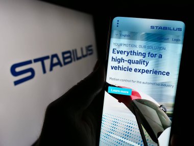 Stuttgart, Almanya - 10-29-2023: Alman hareket kontrol şirketi Stabilus SE 'nin internet sayfası ile iş logosu önünde cep telefonu tutan kişi. Telefon ekranının merkezine odaklan.